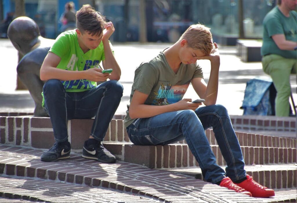 2 jeunes assis davant leur smartphone cyberintimidation